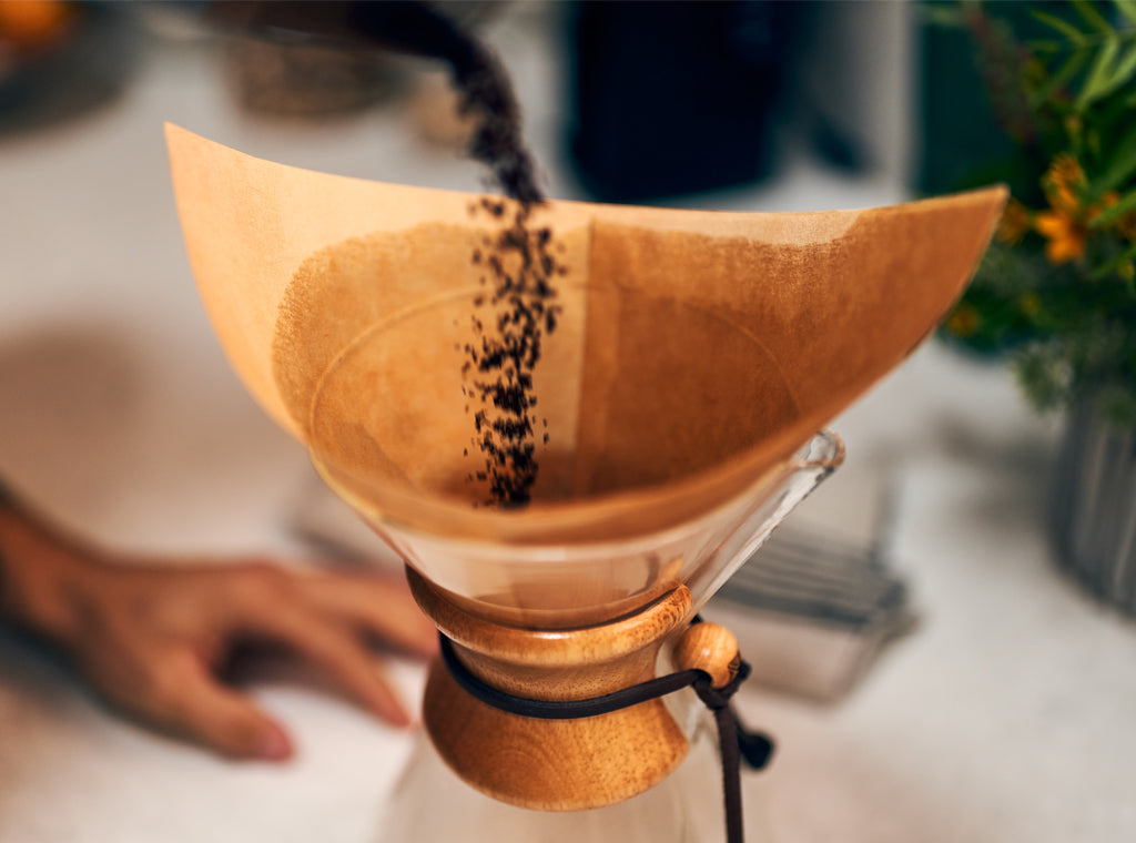 Ground coffee being poured into a Chemex pour over brewer
